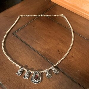 Sterile silver necklace with one red stone pendant.